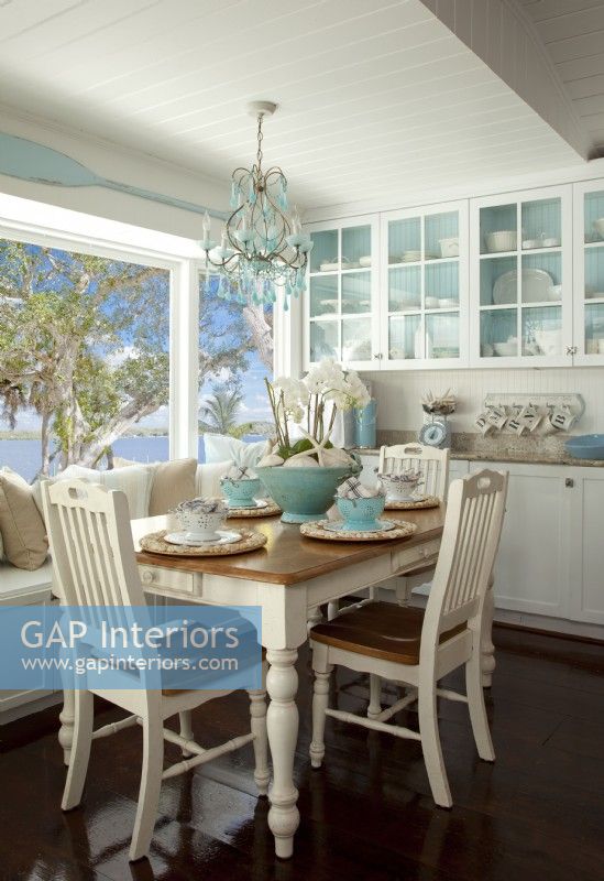 Overlooking the Intercoastal waterways the eating area off the kitchen is the family's favorite spot to share their daily meals. Nikki had the cabinets built-in, and she painted the back a soft sky blue to recall the near-by waters and allow her white dishes to stand out.