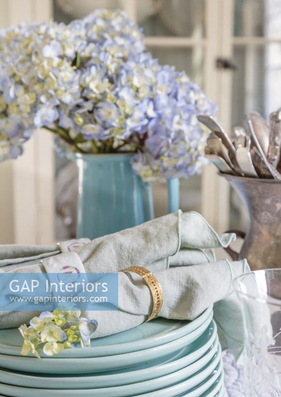 A palette of dusty blues introduces soft color to the table setting. Vintage linen napkins finish the elegant look.