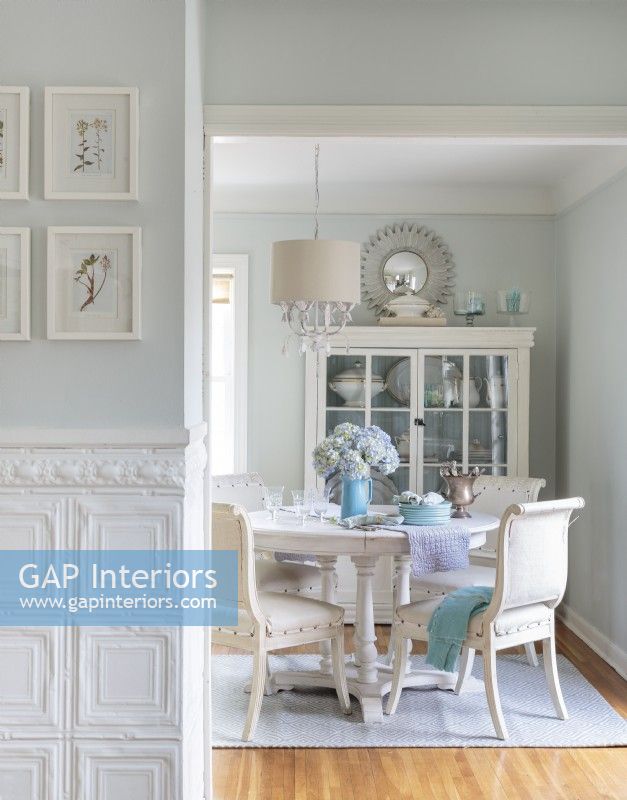 In the dining room, coats of white paint unify secondhand finds into and elegant design set.For something different from traditional wainscoting, Rachel used tin ceiling tiles below the chair rail in the hallway.