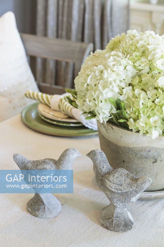 A  stone planter and birds bring a bit of the garden to the dining room table.