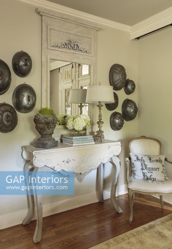 Antique serving domes make an intriguing radial arrangement. They hang on either side of the mirror in a balanced but asymmetrical design statement, in keeping with the coupleâ€™s relaxed style. 