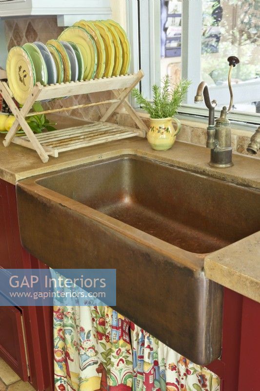 In true farmhouse fashion a sink skirt covers the plumbing below an aged copper basin.
