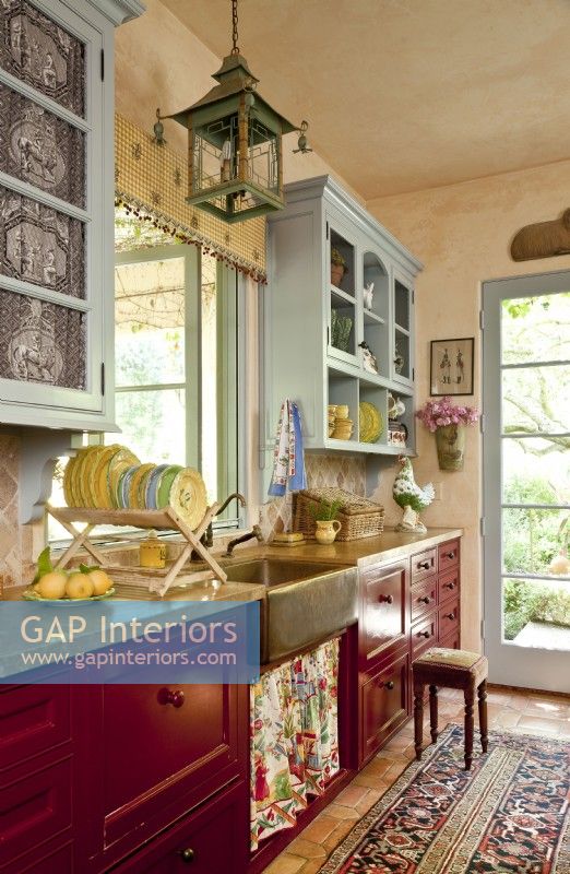 Soft blues, country red and ochre yellows are the basis for the kitchenâ€™s dÃ©cor. The upper cupboards match the roomâ€™s trim while the lower cabinetry sports a rich crimson hue.