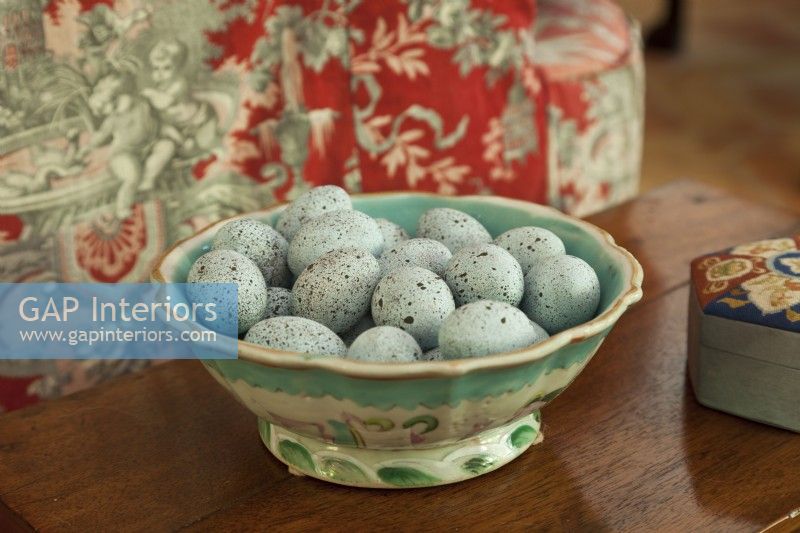 An antique majolica bowl coddles heavenly blue eggs. 

