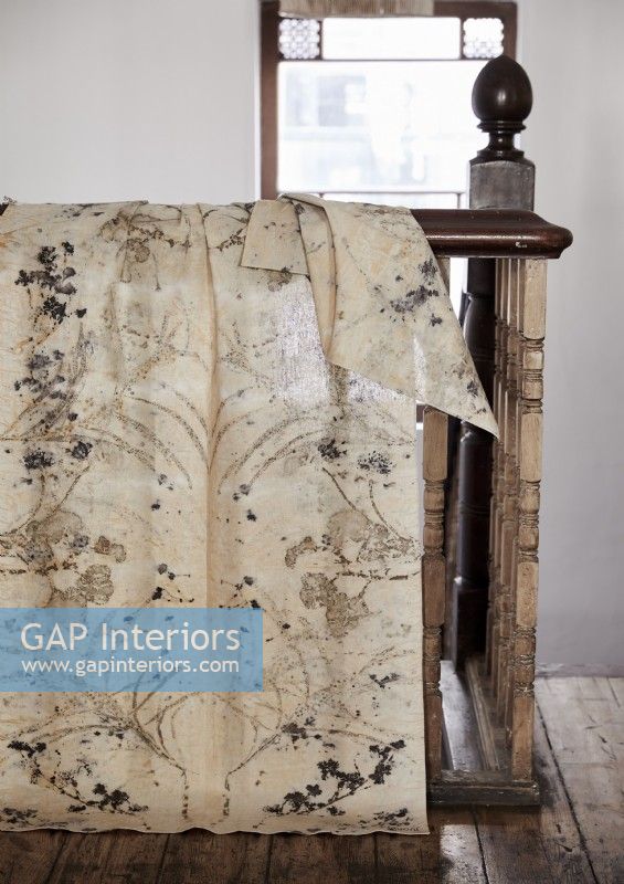 Cream patterned fabric draped over bannisters of wooden staircase