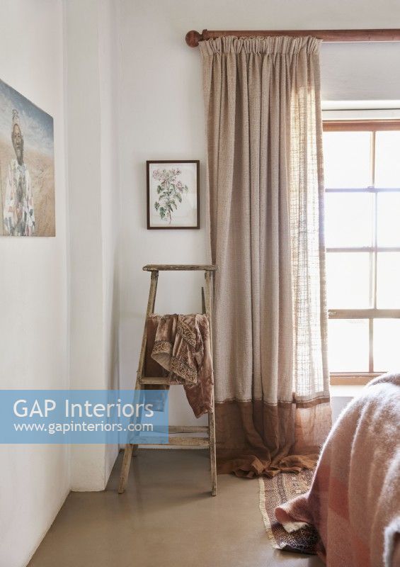 Clothing draped on wooden ladder in feminine country bedroom
