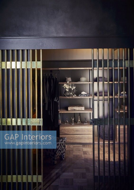 Gold railing doors to classic walk in wardrobes with black walls