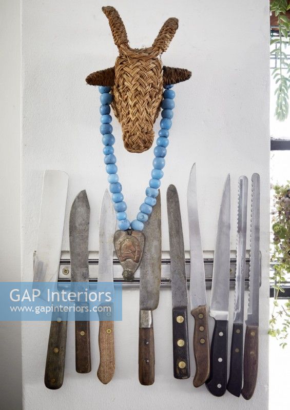 Detail of knives on wall magnet strip with straw bull ornament