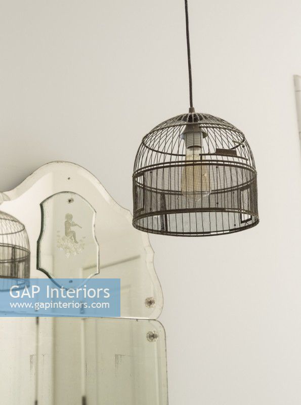 An old birdcage is wired into bathroom light fixture. 