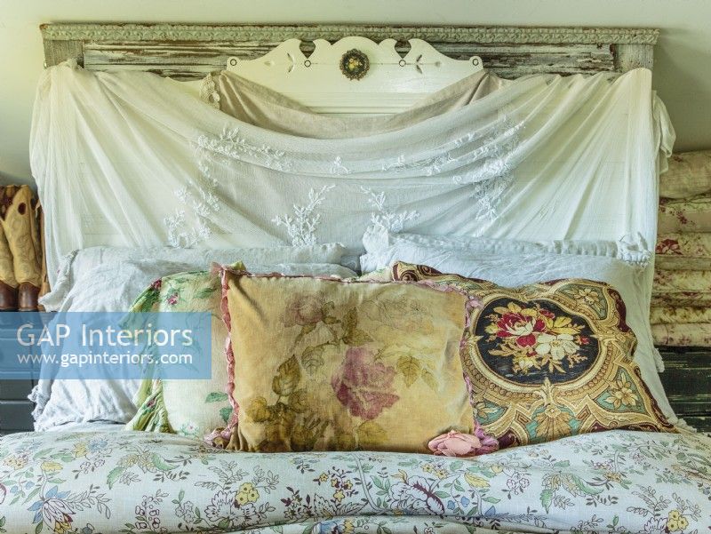 A carved headboard swathed in vintage lace netting and architectural salvage moldings create a dreamy backdrop in the master bedroom. 
