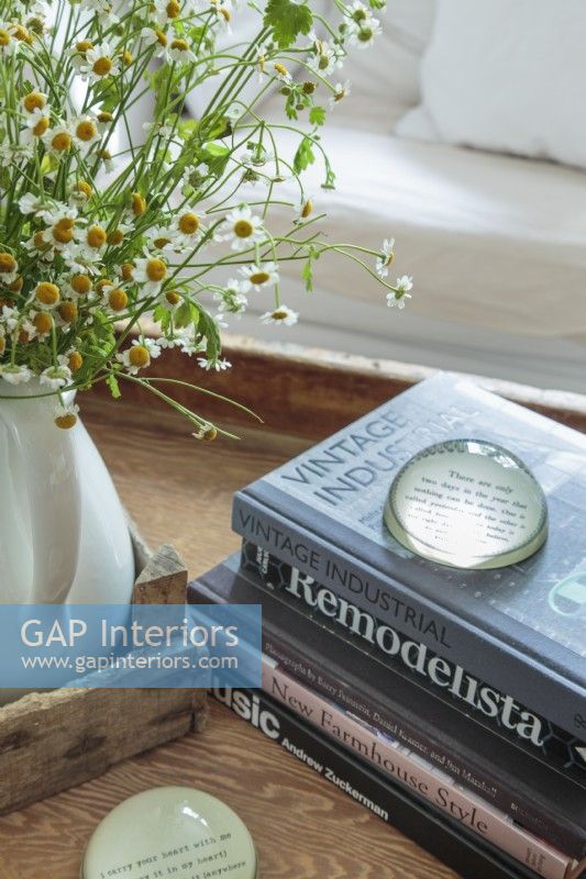 Favorite books and objects are gathered into a vintage wooden tray on a farmhouse table trimmed to coffee-table height.