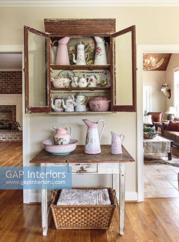 With similar worn brown finishes, a cupboard and a modest table play the part of china cabinet and hutch.