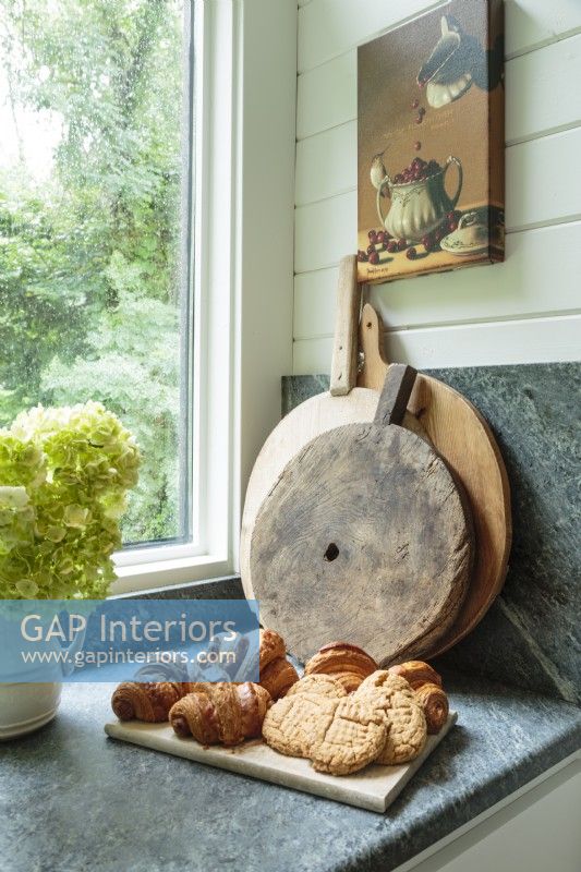 A collection of farmhouse wood breadboards awaits a call to duty on the honed soapstone kitchen counter.
