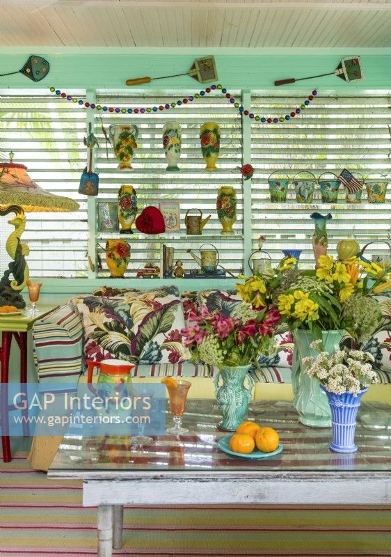 Shelves display collectionS of vases, watering cans and sand pails. The lamp features a one-of-a-kind shade. 