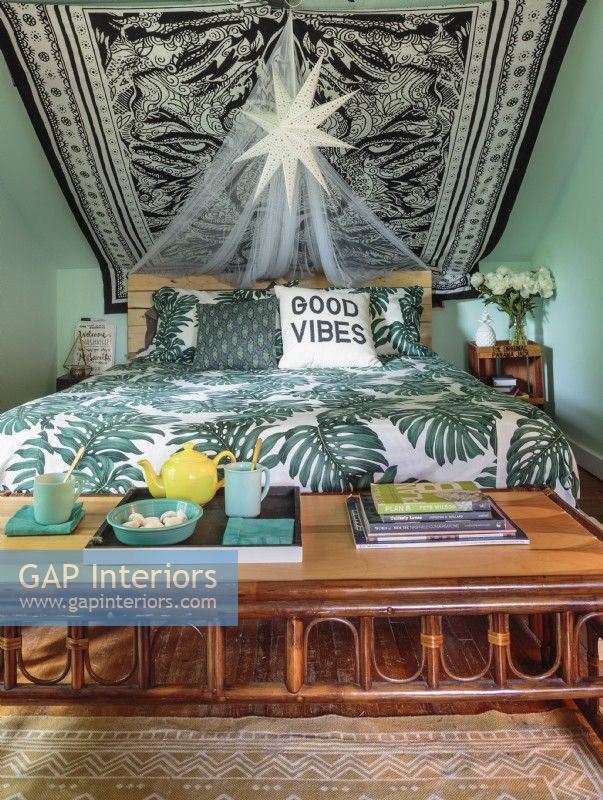 A large-scale leafy duvet set and a low rattan table bring a a tropical vibe to the bedroom.