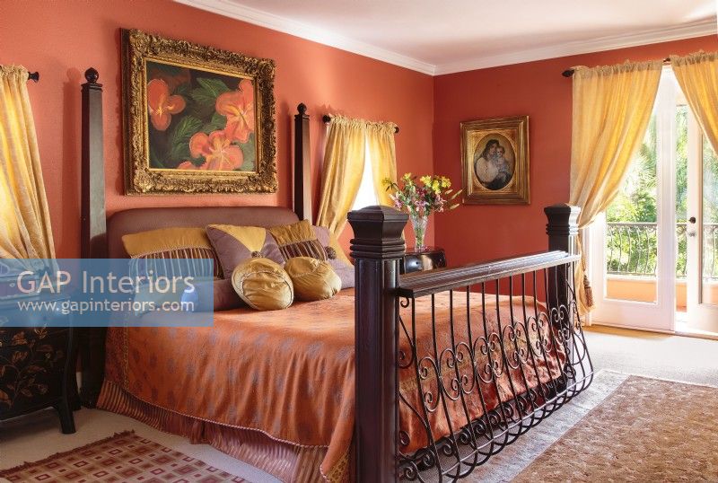 A painting of coral hibiscus in a gilded frame reflects the local flora while echoing the room's dramatic color.
