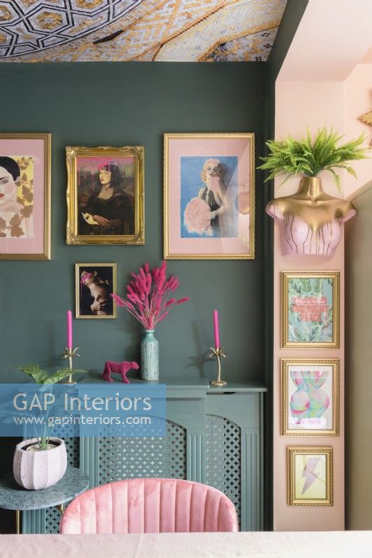 Detail of salon style picture gallery wall and radiator cover in a green and pale pink room