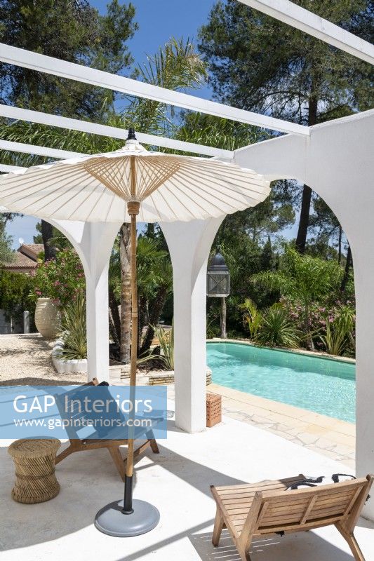 Simple chairs and parasol next to pool in summer