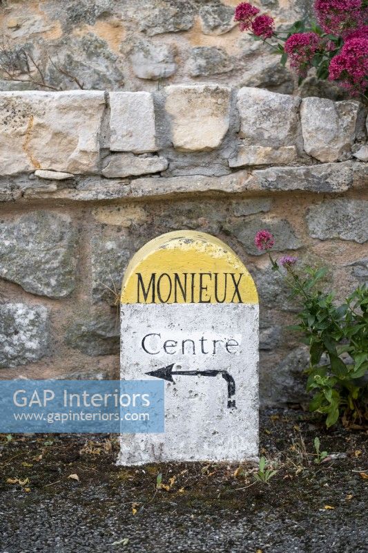 Old French road sign next to stone wall