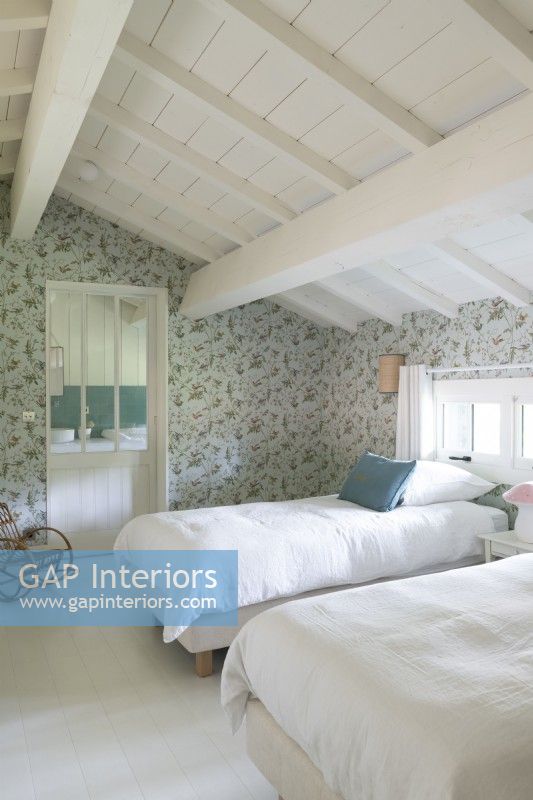 Country bedroom with floral wallpaper and white painted floor 