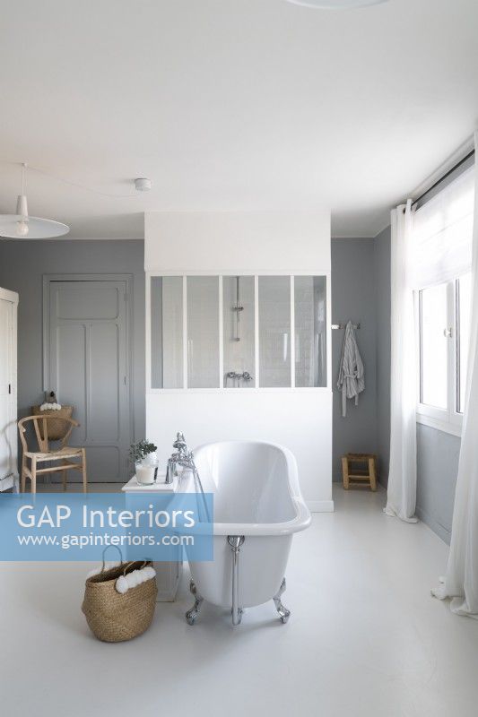 Freestanding bath in centre of large white and grey bathroom