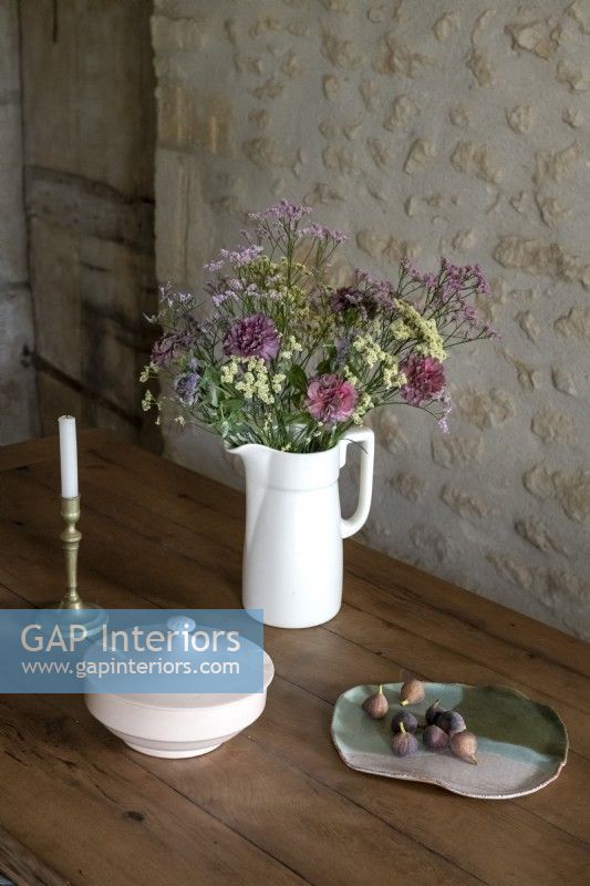 Wild flower arrangement in white jug in rustic dining room