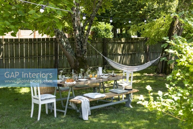 Large picnic table in shade with hammock in country garden