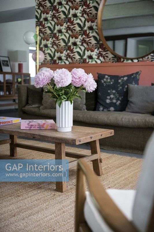 Flowers in vase on wooden coffee table in modern living room