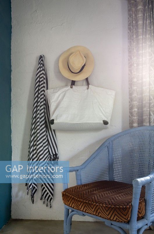 Sarong, bag and sun hat hanging above rattan chair