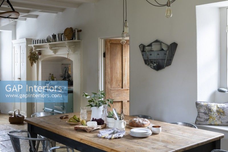 Sally and John Biddle's house in Cornwall, country kitchen, with whitewashed walls and beams. Large kitchen table and Aga cooker.