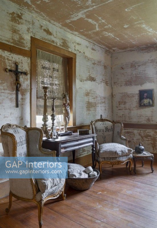 Vintage armchairs in rustic living room with distressed paint on walls