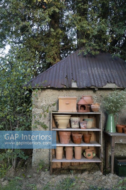 Terracotta pots on outdoor shelving unit against shed