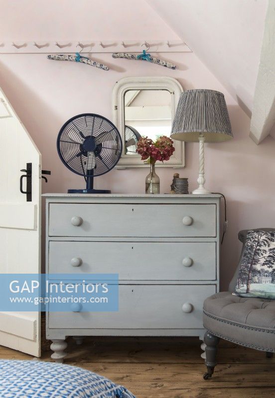 Grey painted wooden chest of drawers in pink bedroom