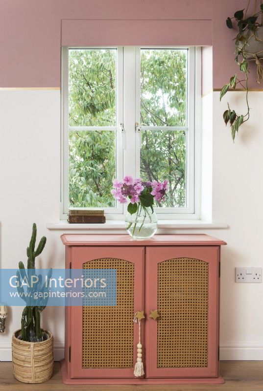 Pink and gold cabinet under window