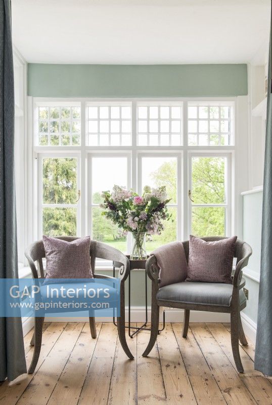 Pair of antique chairs in snug by window with garden views