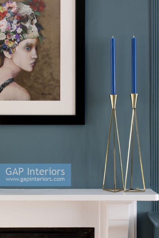 Blue painted walls with botanical art and brass candle sticks