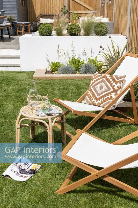 Deckchairs and bamboo side table on lawn