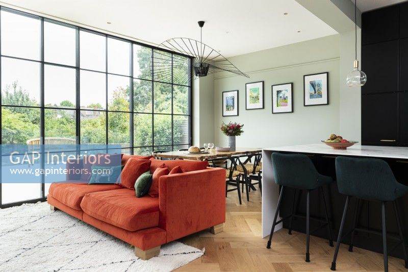 Contemporary open plan dining living area with orange sofa and crittall windows.