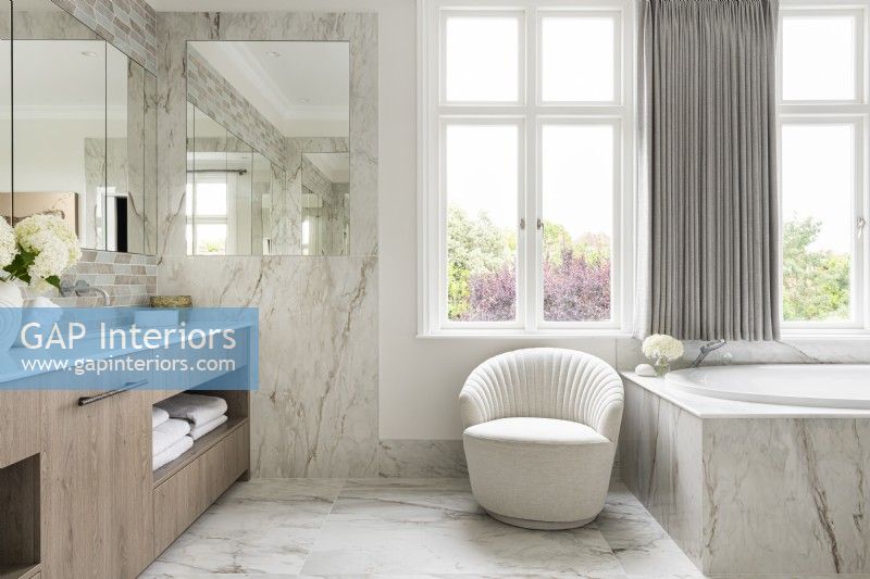 Large classic contemporary bathroom with double vanity units, bath and marble tiles.