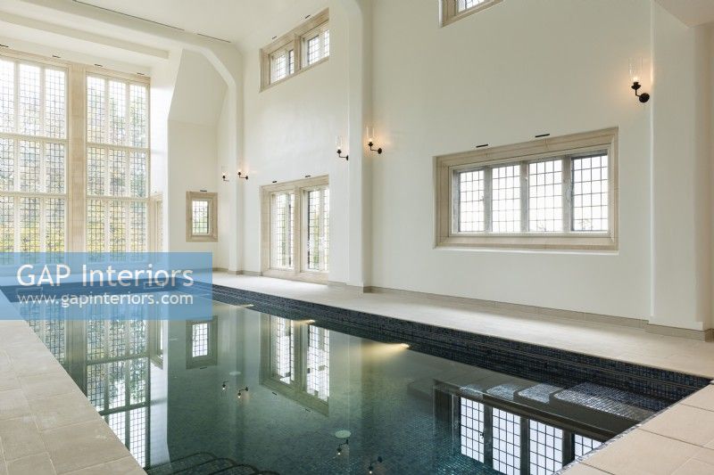 Large indoor swimming pool in a traditional building with floor to ceiling window.