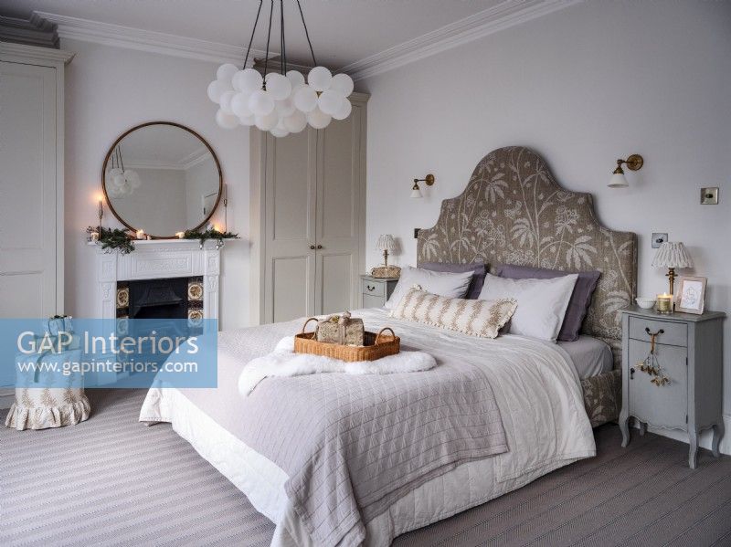 Neutral bedroom with decorative headboard and feature light