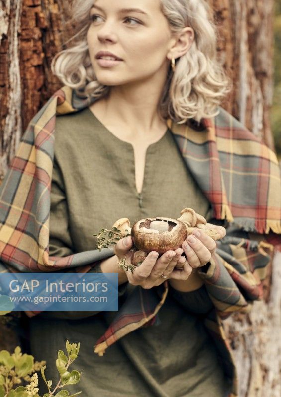 Portrait of young woman holding foraged mushrooms 