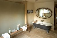 Boonshill Farm, East Sussex. Interior of bathroom with roll top bath, wooden bench from india  and mirror made from old window. 