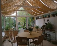 View of country conservatory with roof blinds and dining table and view to garden