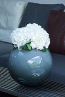 Detail of white hydrangea bloom in spherical blue vase. 