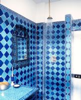 Quirky bathroom with blue tiled walls and open shower 