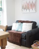 Assorted cushions and throw on leather two seater sofa