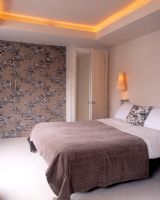 Modern bedroom with wallpapered wardrobe doors and built in lighting 