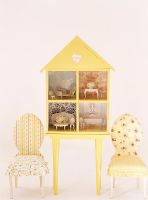 Two chairs on either side of a doll house