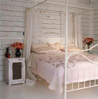 Bedroom with four-poster bed and flowers on side table